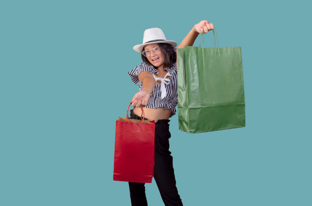 pretty young asian girl with shopping bags and hat on plain backgroundの写真素材