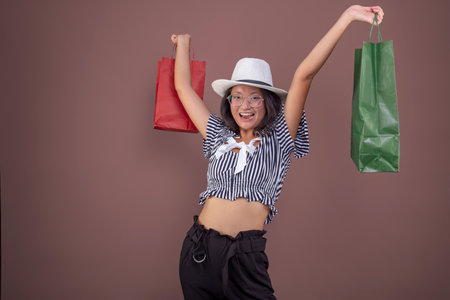young asian girl with shopping bags and hatの写真素材
