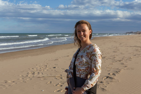 young Caucasian woman walking alone on the sandy beach at sunsetの写真素材
