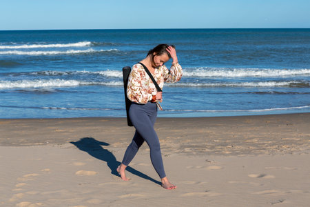 woman walking alone on the sandy beach at sunsetの写真素材