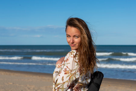 woman walking alone on the sandy beach at sunsetの写真素材