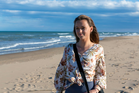woman walking alone on the sandy beach at sunsetの写真素材