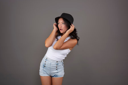 young asian woman posing in shorts, tank top and hatの写真素材