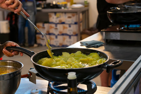 woman frying potatoes to cook a typical food called tortilla de patatas. popular dish of the Spanish gastronomyの写真素材