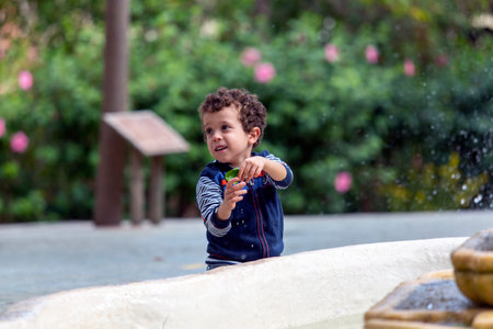 child playing with a leaf next to a fountainの写真素材