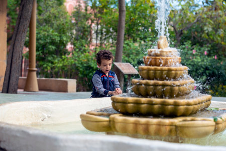 child playing with a leaf next to a fountainの写真素材