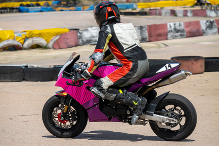 Motorcycle racer in colorful gear rides a pink sports bike on the track, focused on the race.の写真素材