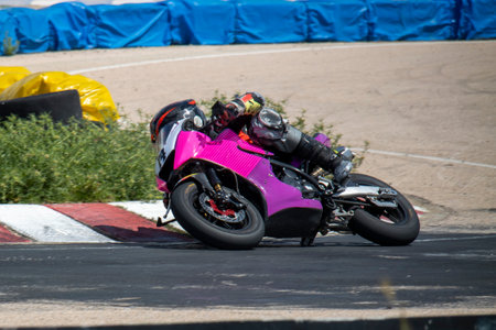 A motorcycle racer in full gear leans sharply into a turn on a race track, showing speed and precision during a competitive event.の写真素材