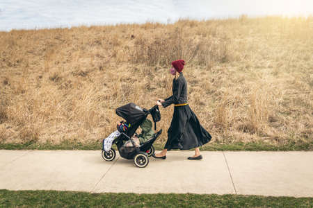 Mother walking her boys through the park in Chicago during quarantine wearing face masksの写真素材