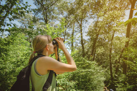 Young woman bird watching with binoculars at Indiana Dunes State Park.の写真素材
