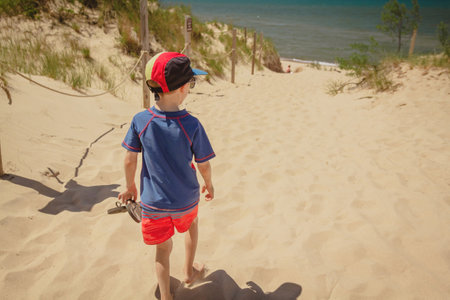 Boy walking along a dune toward West Beach in Indiana Dunes National Park.の写真素材
