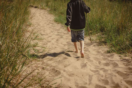 Young boy walking with bare feet on a trail at Indiana Dunes State Park.の写真素材