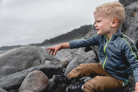 Young boy looking out at the waves on Rialto Beach in National Park.の写真素材