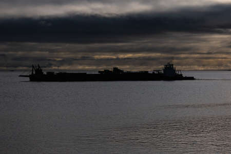Cargo ship in the sea. Dramatic sky with dark clouds.の写真素材