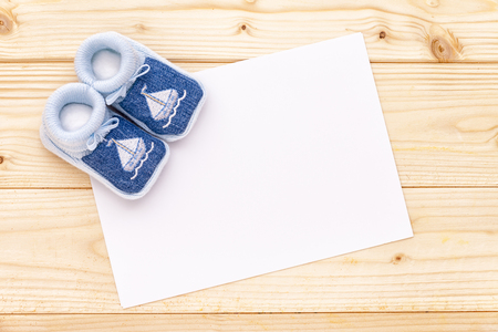 Baby announcement card with baby blue shoes on pine wood background.の写真素材
