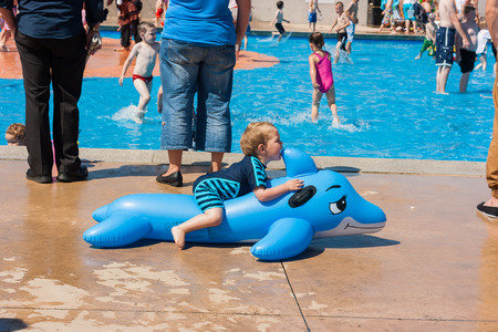 Rhyl, Wales, U.K- August, 9 2012 : Children playing at outdoor paddling pool. Toddler in foreground biting inflatable toy. Rhyl, Great Britain.のeditorial素材