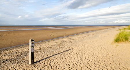 Panoramic Deserted Beach Scene in late afternoon with golden sand, long shadows grass, sea, sky,の写真素材