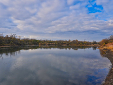 Stunning Fall Scene of Autumn Colored Trees Lining Lake, Bright Blue Sky with Streaking Clouds All...