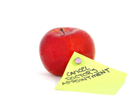 Macro photo of red apple and cancellation reminder on green note with white backgroundの写真素材