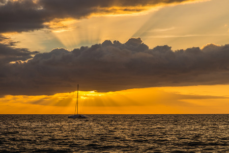 Beautiful scenic warm sunset at the beach in kiehi, Maui, Hawaii. Golden light of ray of sun covered by cloudsの写真素材