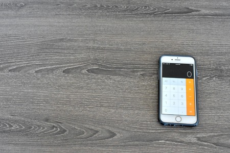 MARYLAND, USA - APRIL 3, 2016: An Apple iPhone 6s displaying the calculator app on a wood surface. The iPhone is a popular product manufactured by Apple Inc.のeditorial素材