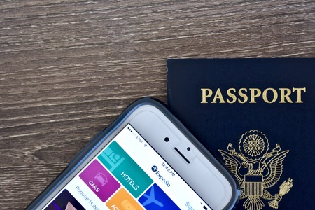 MARYLAND, USA - APRIL 3, 2016: An Apple iPhone 6s displaying the Expedia application homepage on the screen while laying next to an American passport. The iPhone is a product of Apple Inc.のeditorial素材