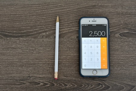 MARYLAND, USA - APRIL 10, 2016: An Apple iPhone 6s displaying the calculator application while laying on a wood surface. The Apple iPhone 6s is a product of Apple Inc.のeditorial素材