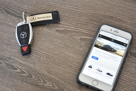 MARYLAND, USA - APRIL 10, 2016: An Apple iPhone 6S displaying the Mercedes-Benz web page while laying next to a Mercedes-Benz key fob.のeditorial素材