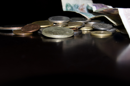International coins and bills reflected on a dark surface top of photo