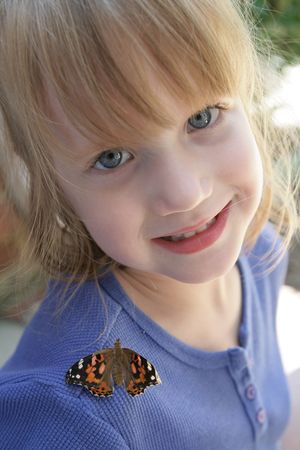 A small child with a butterfly on her shoulderの写真素材