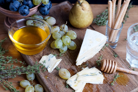 Cambozola cheese served with grapes, honey and pear on a wooden backgroundの写真素材