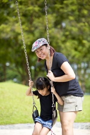 Young Asian family in park playing swingの写真素材