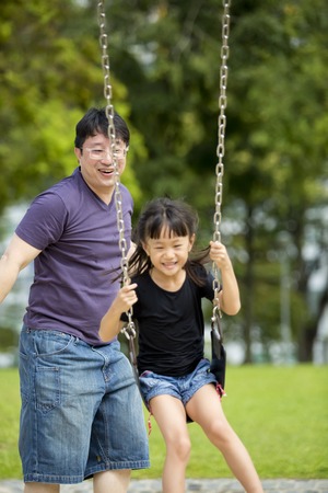 Young Asian family in park playing swingの写真素材
