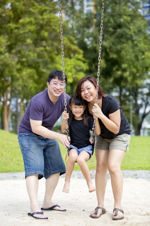 Young Asian family in park playing swingの写真素材