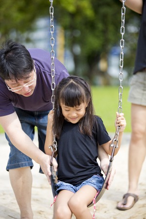 Young Asian family in park playing swingの写真素材