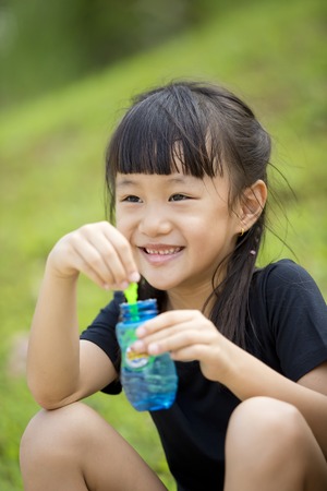 Young Asian girl blowing bubbles in parkの写真素材