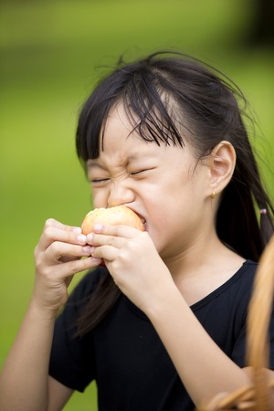 Asian young girl eating orange in parkの写真素材