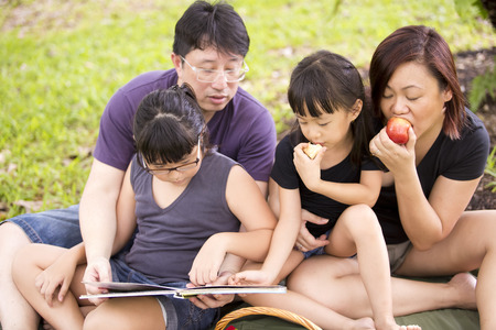 Young Asian family reading in parkの写真素材