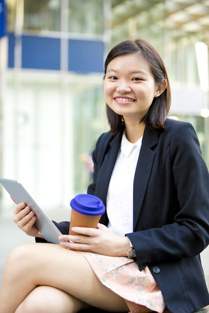 Young Asian female executive drinking coffee and using tablet PCの写真素材