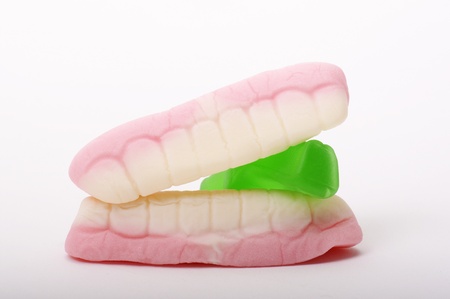 Close up detail of teeth confectionery biting on a green jelly baby lolly