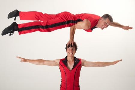 An acrobat balances with one arm on the head of his acrobat partnerの写真素材