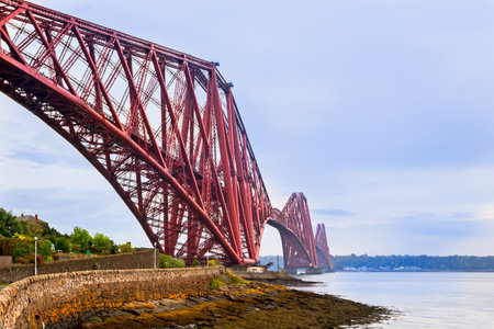 The iconic red Forth Bridge spans the Firth of Forth in Scotland, captured in a scenic landscape...
