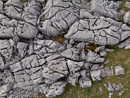An aerial view showcases intricate limestone pavement patterns in a natural landscape, with patches of grass.の写真素材