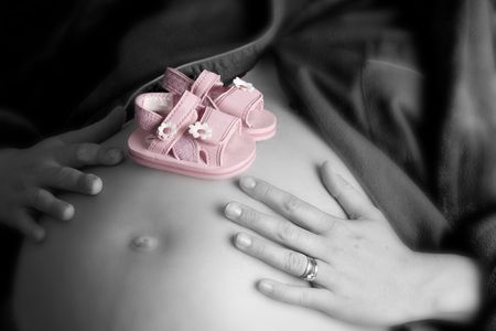 Pregnant woman holding her belly in black and white, with pink shoes in clolourの写真素材
