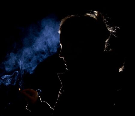 Silhouette or rim light of a Woman lighting a match with blue smokeの写真素材