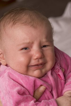 Baby girl dressed in pink crying or about to cry