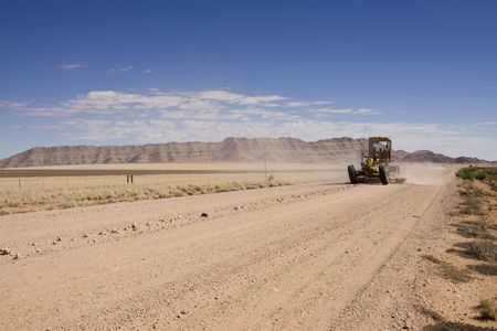 grader on a stretch of dirt road in Namibiaの写真素材
