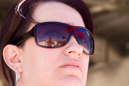Reflection of beach and umbrella in girl's sunglassesの写真素材