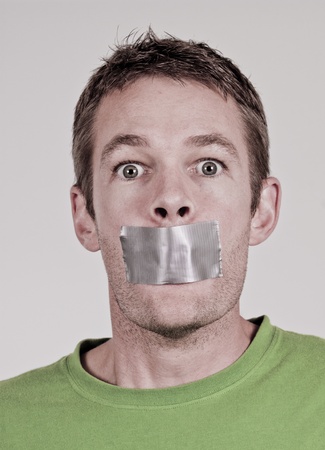 Man with tape over his mouthの写真素材