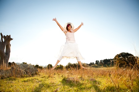 Young woman star jumping in a fieldの写真素材